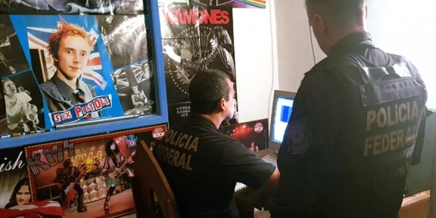 Policiais federais examinam computador na casa de suspeito